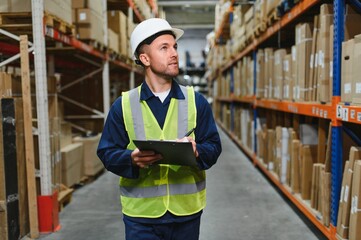 Portrait of warehouseman with clipboard checking delivery, stock in warehouse. Warehouse worker...