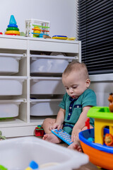 A baby sits on the floor, happily playing with toys