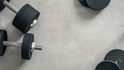 Heavy dumbbells arranged on a gray workout surface for strength training and fitness activities. Copy space texture background. © Mr. Music