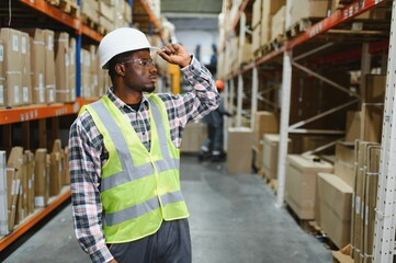 Portrait of a handsome african american warehouse worker in overalls and a helmet