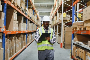 Portrait of african american warehouseman with clipboard checking delivery, stock in warehouse....