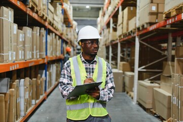 Portrait of african american warehouseman with clipboard checking delivery, stock in warehouse....