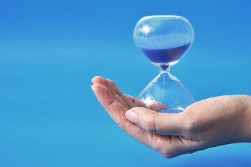 An hourglass in a person's hand, the concept of time and deadlines in life