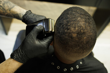 Fototapeta premium Top view of hairstylist trimming head of african american customer