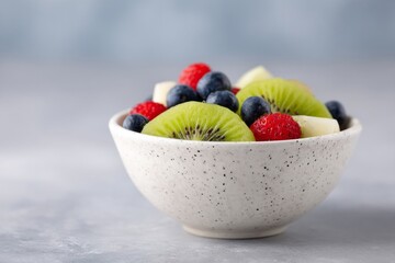 Speckled porcelain cradles freshly sliced kiwi, blueberries, and raspberries, embodying midsummer indulgence and Fruitarian Enlightenment Day delights