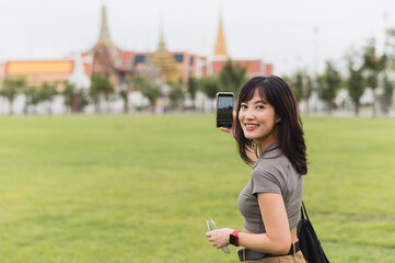 Happy southeast asian woman teenager blogger on solo world travel uses smartphone to take photo....