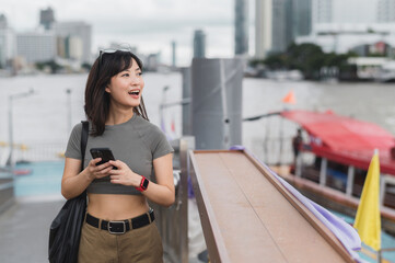 Happy young southeast asian woman teenager blogger world travel explorer using smartphone searching...