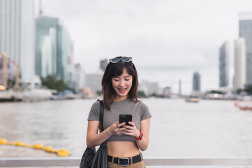 Young southeast asian woman teenager blogger searching map smartphone for guide near chao phraya river bangkok thailand. world travel explorer concept for local cultural experience asia tourism