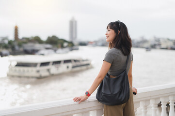 Solo Southeast Asian woman teenager blogger and world travel explorer enjoying local cultural experience and tourism concept to wait for an express boat Chao Phraya river Bangkok Thailand Asia
