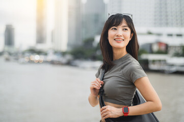 Happy young southeast asian woman solo travel blogger enjoying tourism in Bangkok Thailand. local cultural experience for teenager explorer by Chao Phraya River in Asia