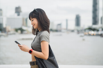 Young southeast asian woman teenager blogger explorer using smartphone searching travel guide. World tourism concept for local cultural experience in Bangkok Asia by Chao Phraya river