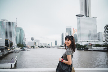 Joyful young solo southeast asian woman and teenager blogger with smartphone. world travel explorer concept for local cultural experience on Chao Phraya River in Bangkok Thailand Asia tourism