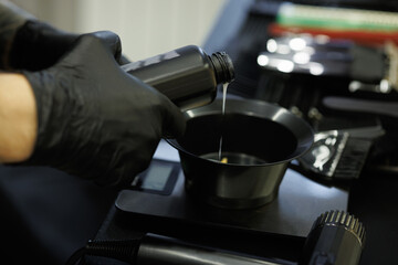 Close up of barber in latex gloves pouring color dye in barbershop 