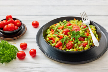 succotash of corn, beans, tomatoes, in black bowl
