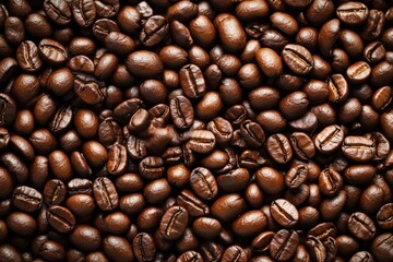 Obraz premium Close-up of shiny, roasted coffee beans densely packed, showcasing rich brown tones and textured surfaces.