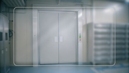 Large industrial elevator doors in a clean, modern facility with a control panel on the right and metallic surfaces surrounding the entrance.
