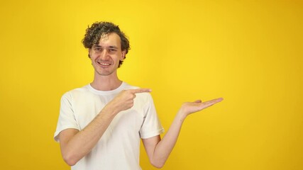 Excited happy young man student pointing aside with fingers at copyspace, isolated on yellow background — dynamic visual ideal for advertising, e-commerce, education, World Youth Skills Day campaigns