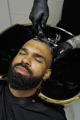 Top view of barber washing head of young african american client 