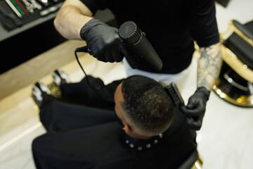 Overhead view of barber drying hair of african american man in barbershop