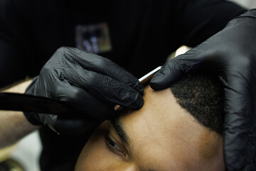 Close up of barber doing haircut to african american client with razor 