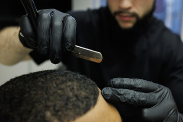 Partial shot of blurred barber holding razor above head of client