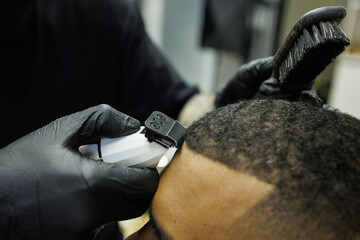 Close up of barber trimming hair of african american client in barbershop