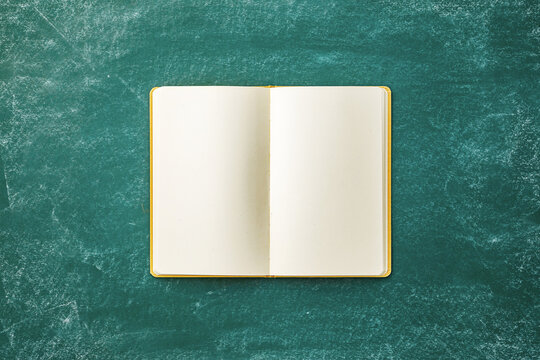 New blank notebook on green chalkboard ready for back to school activities, studying and creative writing.