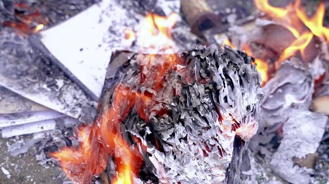 Burnt paper documents, books in a landfill. Ash and smoke from burning paper. Flame.