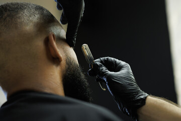 Close up of barber shaving african american client with razor 