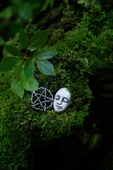 Mystery stone face and pentacle amulet on moss, natural abstract background. Fantasy mystical image...