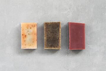 Organic soap bars in earthy tones arranged on a minimalist concrete background