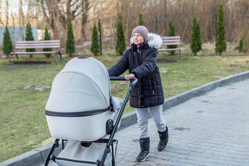 Tween girl walking with baby stroller outside