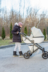 Girl in winter clothes pushing baby stroller