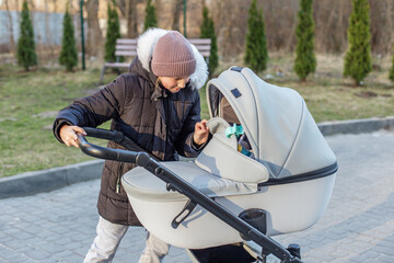 Girl checking on baby inside stroller outdoors