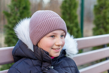 Smiling preteen girl in winter hat outdoors.