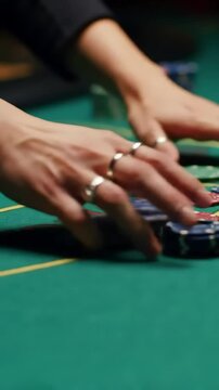 Casino dealers rhythmic hands skillfully shuffle and collect poker chips, creating a captivating clatter at the gaming table &ndash; a dynamic scene of chance and excitement.