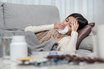 Young Asian woman having high fever while checking body temperature, female sneezing and runny nose with seasonal influenza, taking medicine, virus, coronavirus, illness, respiratory, allergic