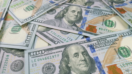 A stack of U.S. hundred dollar bills on a table representing wealth and financial resources