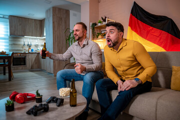 Friends celebrating a sports event at home with drinks and snacks