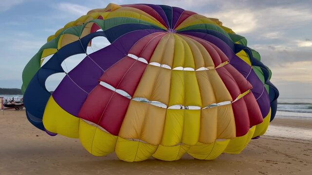 Colorful parasailing parachute on the beach. Beautiful colorful parachute attached to the beach. Extreme excursions.
