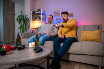 Friends enjoy television night with drinks and snacks in cozy living room