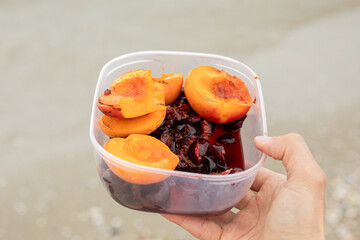 container with fruits in hand against the sea in summer