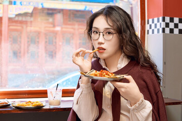 Oriental women eating a lot at the Meiyan hot dog fast food restaurant