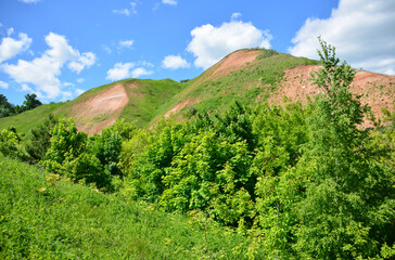 Fototapeta premium Scenic landscape of rolling hills and lush greenery under a bright blue sky