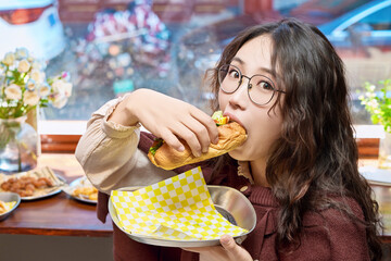 Oriental women eating a lot at the Meiyan hot dog fast food restaurant