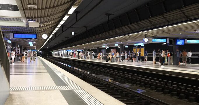 01-07-2025 Zurich, Switzerland. People waiting for the train inside underground main train station platforms. Wide angle view, real time