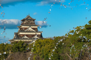 Airborne water droplets from a fountain create sparkling, dynamic frame for the historic Hiroshima Castle. Unique perspective captures iconic Japanese landmark in Hiroshima, Japan, on a beautiful day