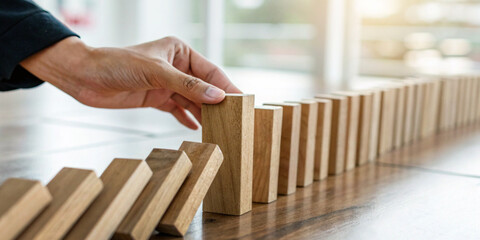 Abstract background. Hand stopping falling wooden dominoes in the concept of business risk management and the strategic planning of good leaders with foresight