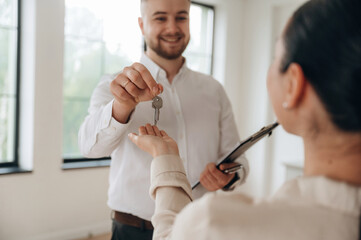 Giving the keys, happy new owner. Man and woman are in the modern new room, conception of business