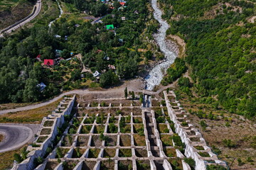 A protective dam in the Talgar gorge. A mountainous area with different vegetation and a river.